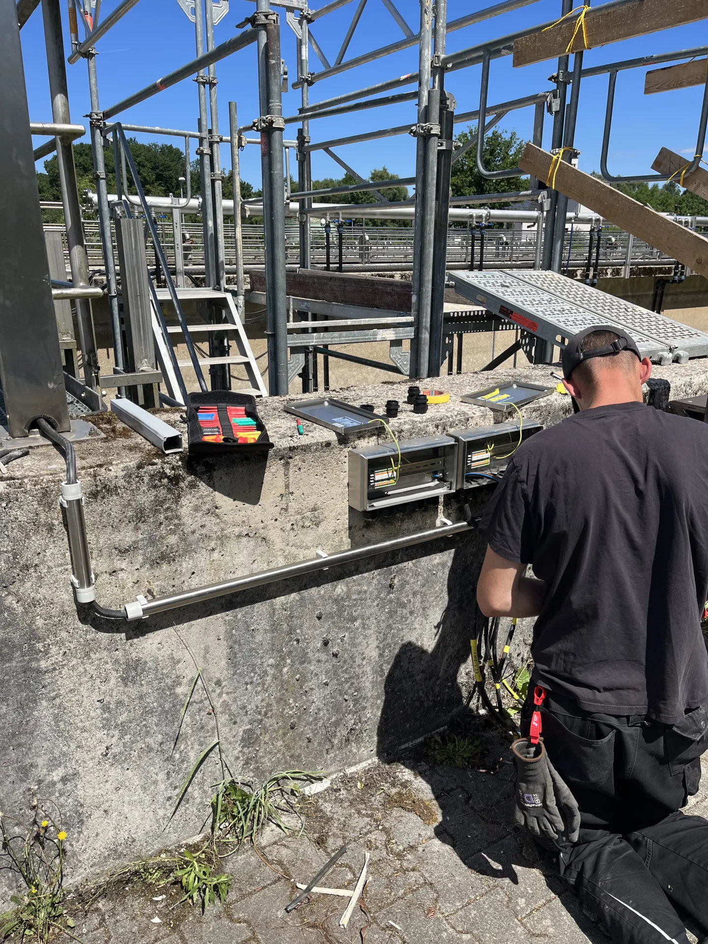 Electrician installing outdoor junction boxes on industrial concrete wall