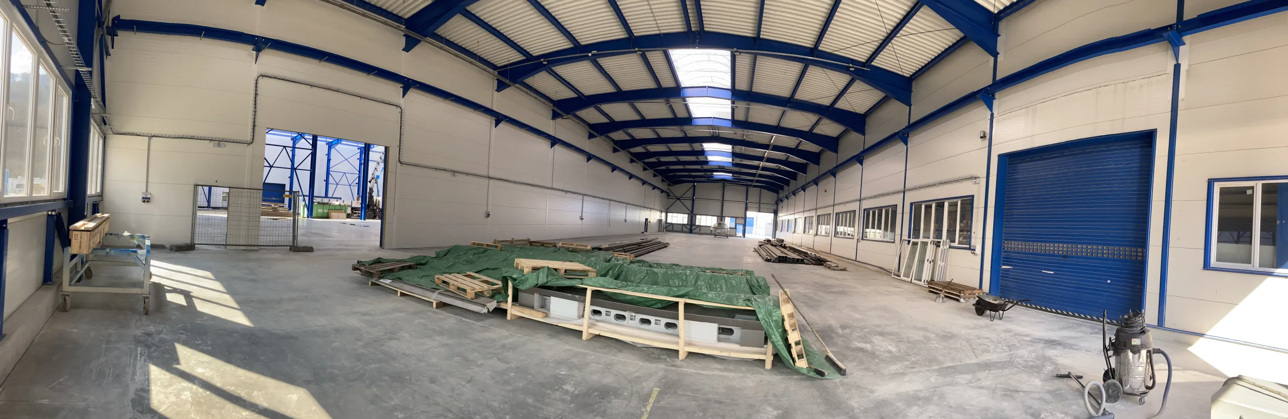 Modern industrial warehouse interior with blue steel beams and skylights