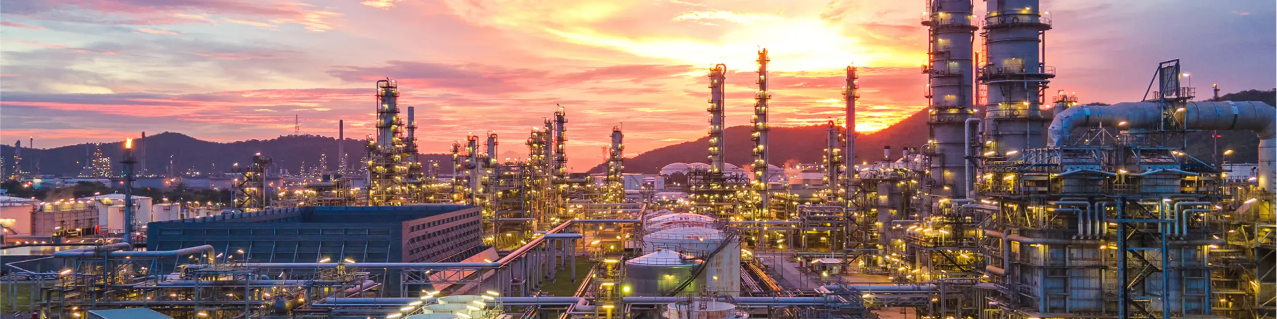 Oil refinery panorama at sunset with illuminated industrial towers