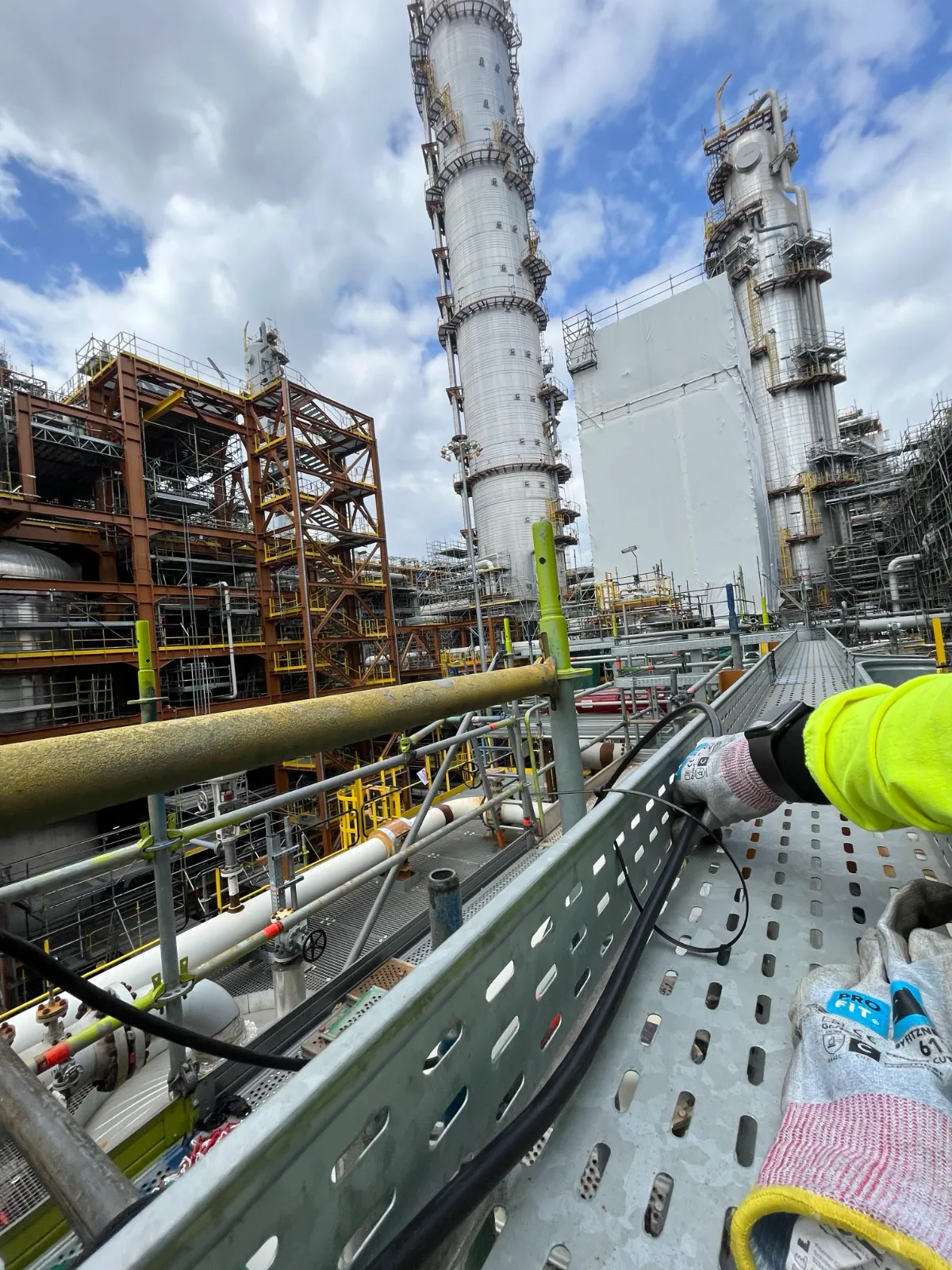 Worker on scaffolding at industrial refinery with distillation towers